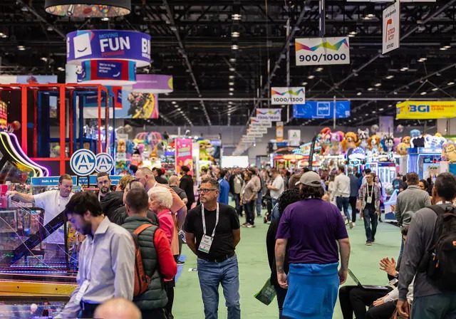 Visitors exploring amusement rides, arcade games and attractions on the busy IAAPA Expo trade show floor